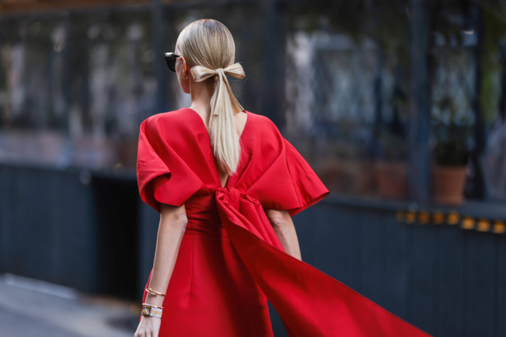 πώς να ντυθείς τις γιορτές 2023 – γυναίκα με κομψό μακρύ κόκκινο φόρεμα με φιόγκο στην πλάτη