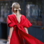 πώς να ντυθείς τις γιορτές 2023 – γυναίκα με κομψό μακρύ κόκκινο φόρεμα με φιόγκο στην πλάτη